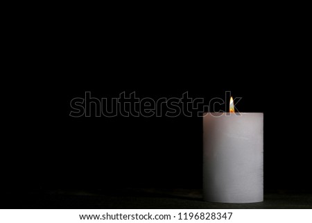 White burning candle on black background