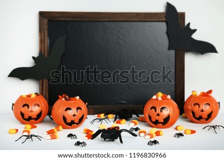 Pumpkin buckets with candy corns and black frame on grey background