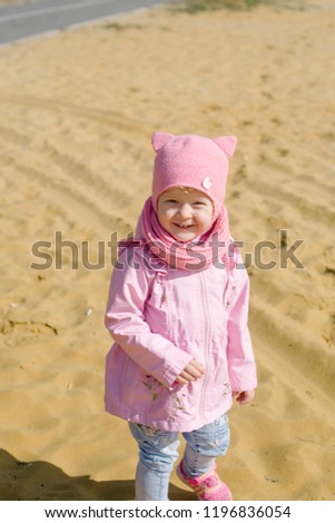 Little girl in a pink hat on the waterfront