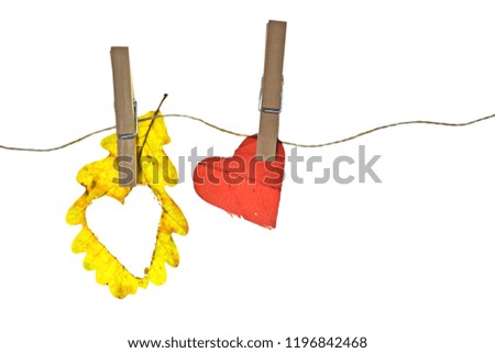 A colorful autumn leaf from whose center the shape of a heart was cut out hangs on a clothesline - Isolated autumn leaf on a clothesline as a symbol of the love of autumn
