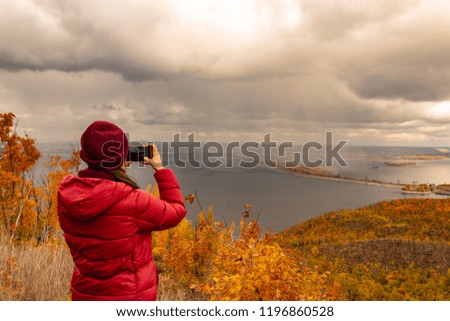 girl takes pictures of clouds and rain over the river