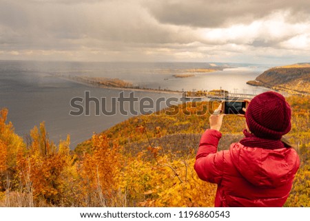 girl takes pictures of clouds and rain over the river