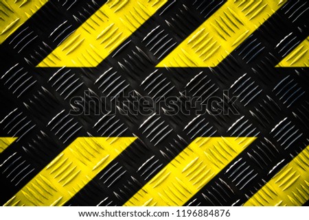 Warning sign yellow and black stripes painted on steel checker plate (or diamond plate) on the floor texture background with empty text space. Concept do not enter area, caution, danger, hazard.