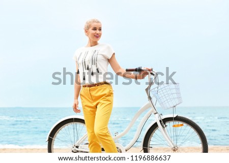 Beautiful woman in casual outfit with bicycle on sea coast