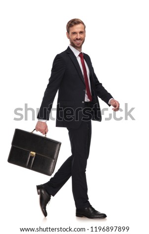 side view of cheerful businessman swinging his suitcase and walking on white background, full body picture
