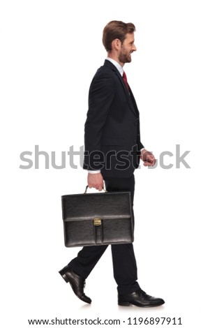 side view of handsome businessman holding suitcase walking and smiling on white background full body picture