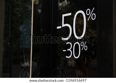 on the shop window, glass, written discounts of fifty percent and thirty percent. Black Friday, Christmas discounts, New Year discounts. Buying gifts in the store. black showcase on which you can