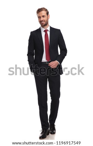 relaxed businessman walking on white background and looking to side while smiling, full length picture