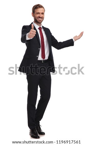 joyful businessman invites and makes thumbs up sign while standing on white background, full length picture