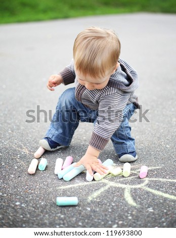 little beautiful boy draws with chalk on asphalt