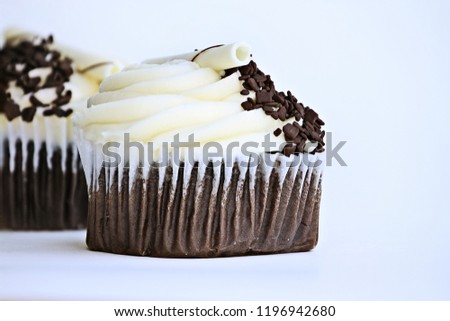 Pretty chocolate flavored cupcake with buttercream icing. Decorated with white chocolate curls and dark chocolate chips.