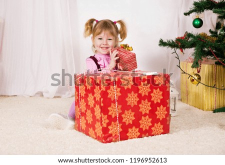 little girl with Christmas gifts near the Christmas tree