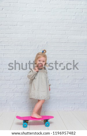 the girl, child on a skateboard on a white brick wall background