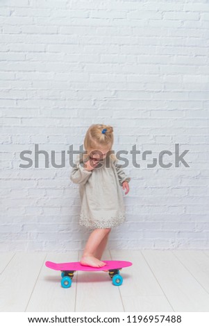 the girl, child on a skateboard on a white brick wall background