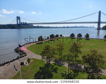 Aerial view of American flag with George Washington Bridge in Fort Lee, NJ on the background. George Washington Bridge is a suspension bridge spanning the Hudson River connecting NJ to Manhattan, NY.