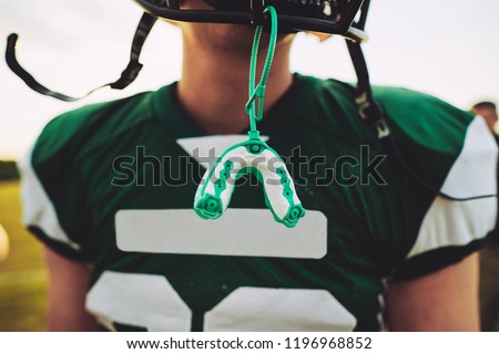 Closeup of a mouthguard hanging off the helmet of an American football player during a team practice session Royalty-Free Stock Photo #1196968852