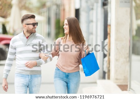 Young couple with shopping bags smiling and walking outdoors
