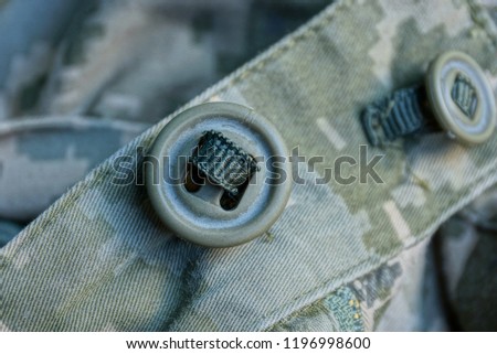 one big green button on camouflage army clothes