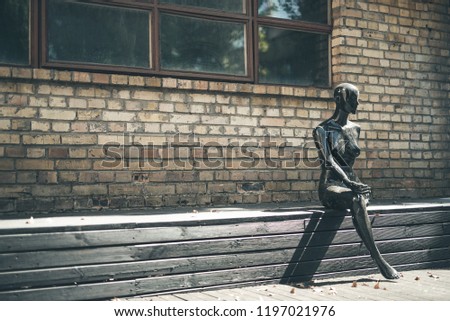 Mannequin sitting. Useless female mannequin with one leg sitting against the brick wall outdoors