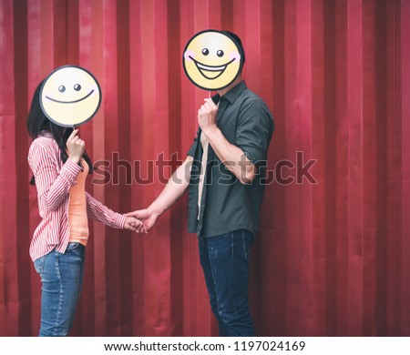 Cute smiles. Unusual young couple having fun and holding funny smiles near their faces while being outdoors and holding hands
