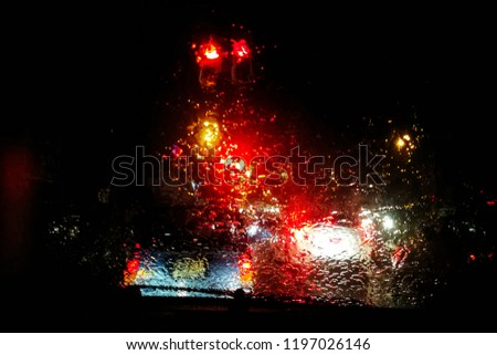 Blur pictures of cars are parked waiting for a red traffic light at night in heavy rain and poor visibility.