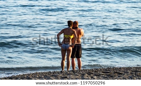Silhouettes of man taking pictures of a  girl who is laying with waves at the beach in KONAKLI, ALANYA, TURKEY. 
