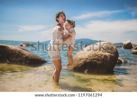 Lifestyle portrait mom and daughter in happines at the outside in the meadow.Happy loving family. Mother and child girl playing, kissing and hugging.Asian mother and daughter walking on the beach.