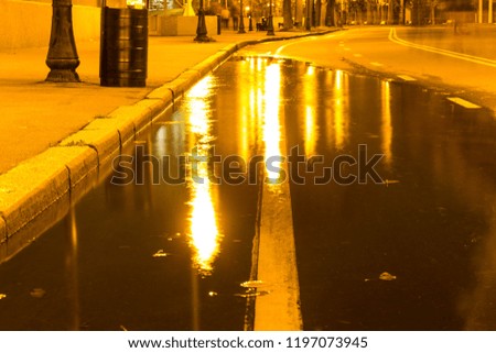 Autumn. A puddle on the pavement with a reflection of lanterns in the evening. Autumn weather.