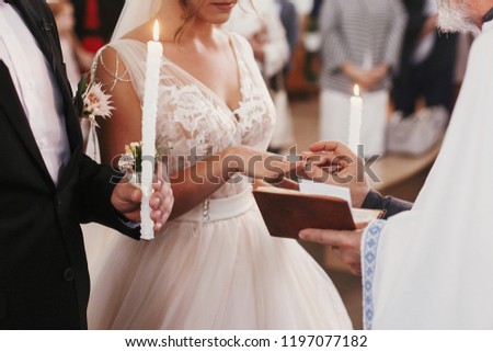 Priest putting on golden wedding ring on bride finger. Wedding matrimony in church. Exchanging wedding rings Royalty-Free Stock Photo #1197077182