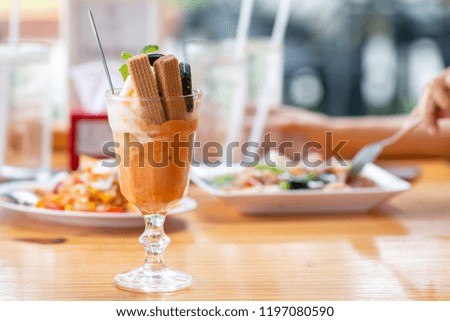Vanilla sundae ice cream with wafer in a glass served on wooden desk in Asia canteen.