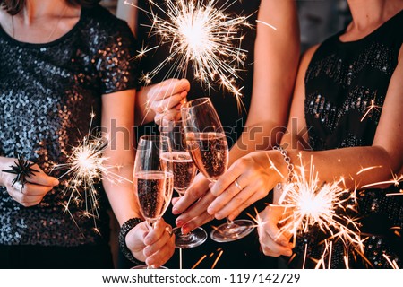 Friends celebrating Christmas or New Year eve party with Bengal lights and rose champagne. Royalty-Free Stock Photo #1197142729