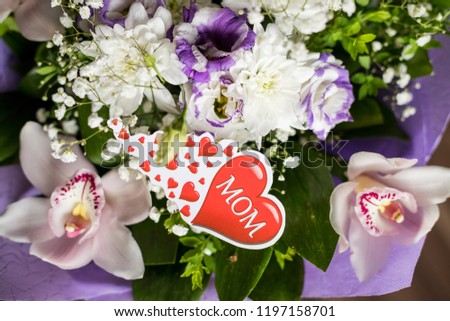 Text Love you Mom and heart shape, flowers background. Happy Mother's Day greeting card. Flat lay.bouquet with orchids flowers and lisianthus. mothers day. Natural flowers. Floral gift. Romantic love