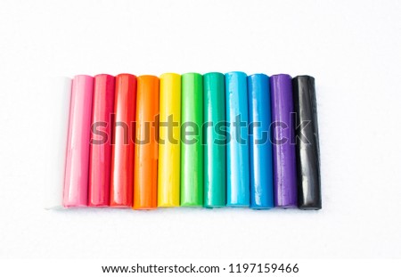 Beautiful rainbow colored plasticine clay arrange on white background, cute colorful sticks dough.