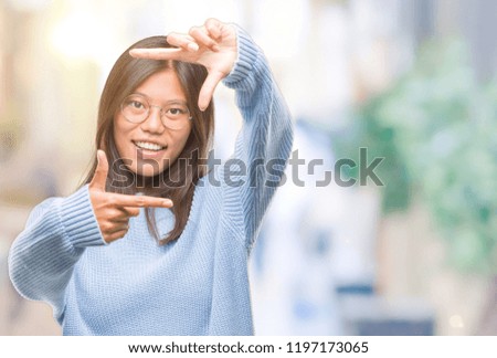 Young asian woman wearing winter sweater over isolated background smiling making frame with hands and fingers with happy face. Creativity and photography concept.