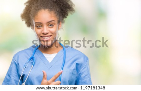 Young afro american doctor woman over isolated background cheerful with a smile of face pointing with hand and finger up to the side with happy and natural expression on face looking at the camera.