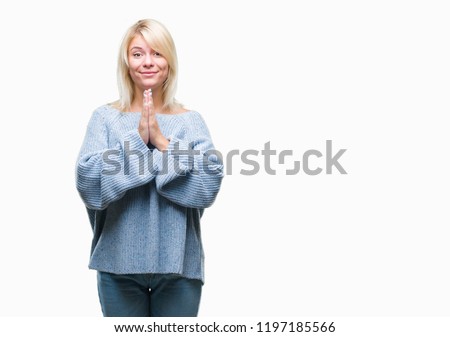 Young beautiful blonde woman wearing winter sweater over isolated background praying with hands together asking for forgiveness smiling confident.