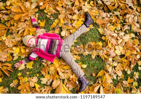 cute girl lying in autumn leaves in the park