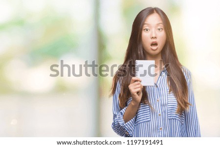 Young asian woman holding notebook over isolated background scared in shock with a surprise face, afraid and excited with fear expression