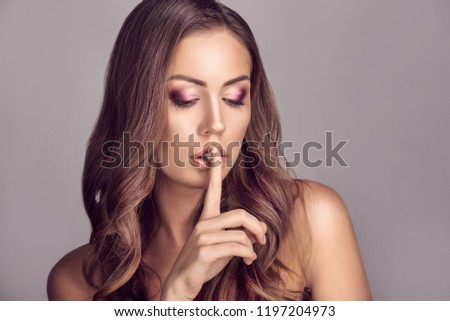 Portrait of beautiful woman showing silence sign with finger