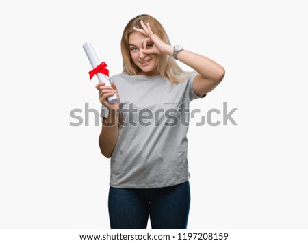 Young caucasian woman holding degree over isolated background with happy face smiling doing ok sign with hand on eye looking through fingers