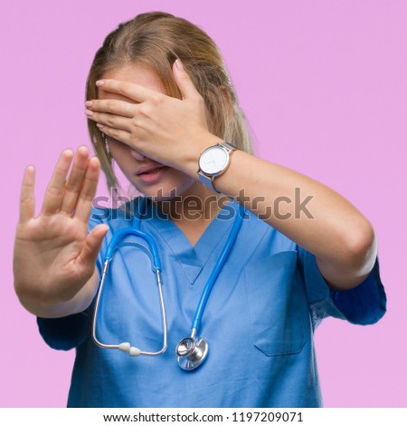 Young caucasian doctor woman wearing surgeon uniform over isolated background covering eyes with hands and doing stop gesture with sad and fear expression. Embarrassed and negative concept.