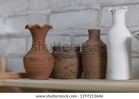 Ceramic vases and containers of different shapes on a wooden shelf. Design. Home comfort