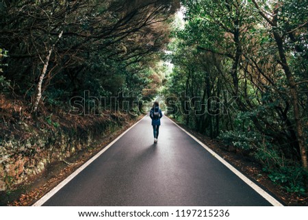 Young traveler woman walking on the road and forest background. Travel concept