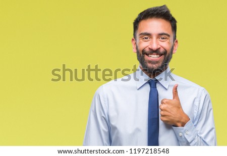 Adult hispanic business man over isolated background doing happy thumbs up gesture with hand. Approving expression looking at the camera with showing success.