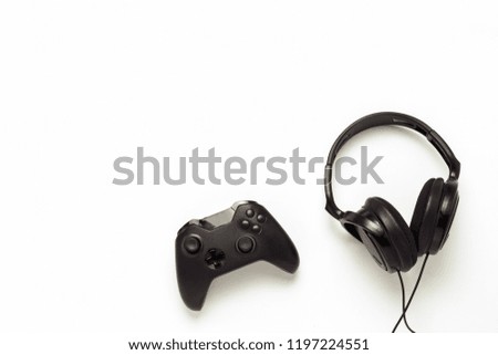Black headphones and a gamepad on a white isolated background. C
