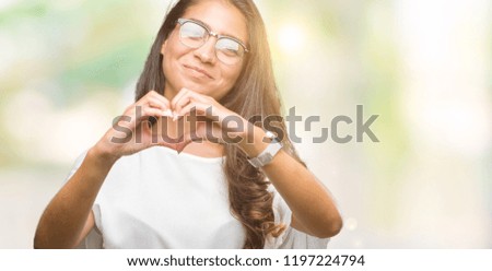 Young beautiful arab woman wearing glasses over isolated background smiling in love showing heart symbol and shape with hands. Romantic concept.