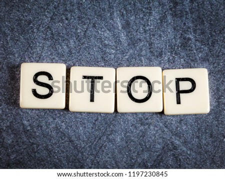 Letter tiles on black slate background spelling Stop