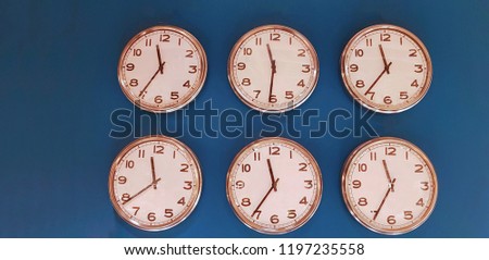 Six wall clocks with twelve hour clock face on blue background