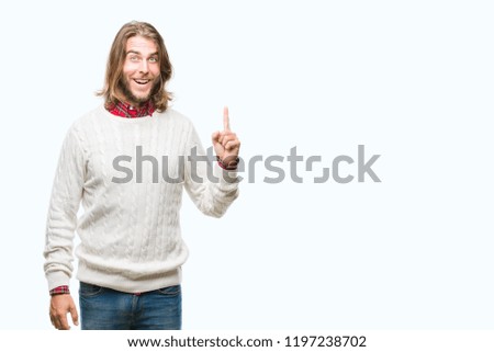 Young handsome man with long hair wearing winter sweater over isolated background pointing finger up with successful idea. Exited and happy. Number one.