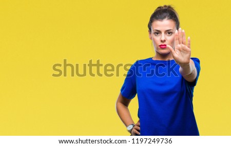 Young beautiful woman wearing casual blue t-shirt over isolated background doing stop sing with palm of the hand. Warning expression with negative and serious gesture on the face.